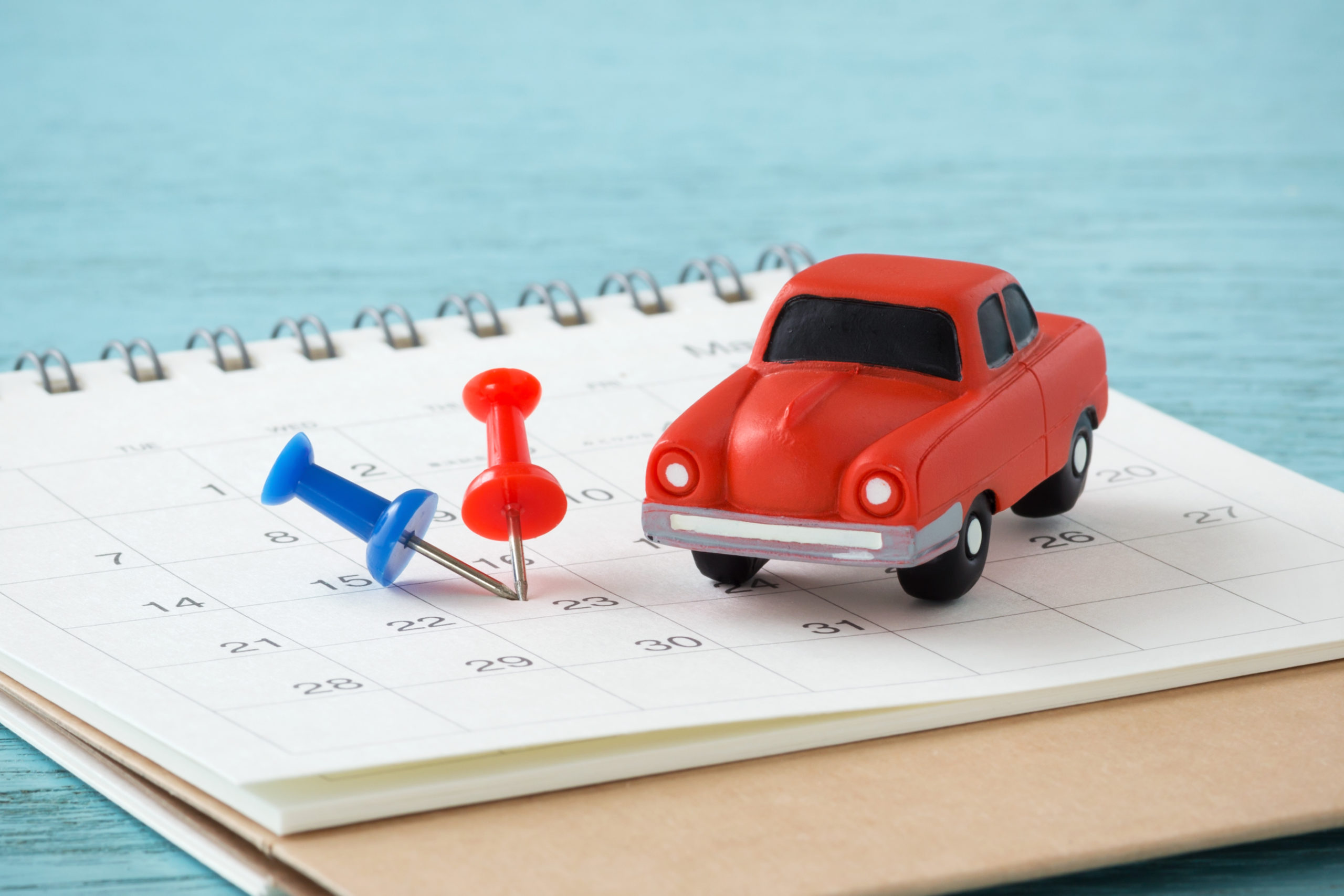 Red toy car and pins on calendar